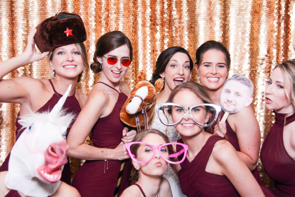 bridemaids posing with funny props on a gold backdrop