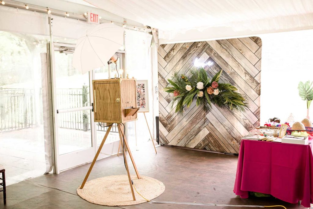 vintage photo booth front of a rustic backdrop and tropical arrangement 