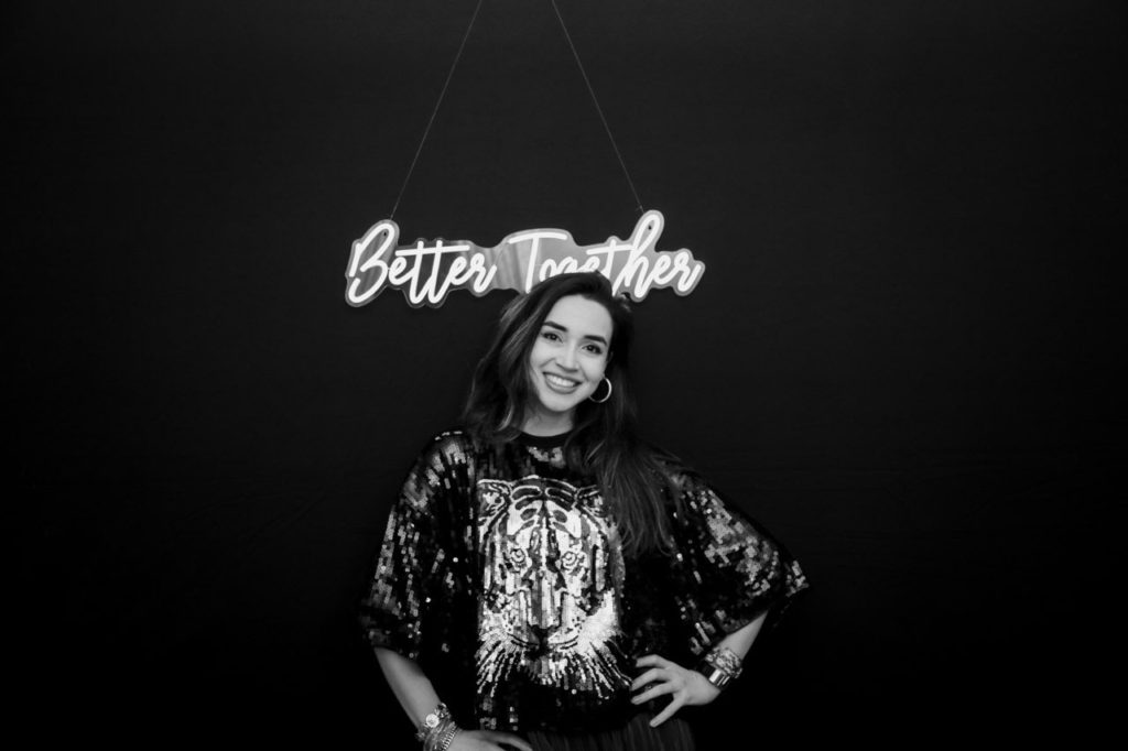 black and white photo on a black background with a neon sign on top of a girl smiling